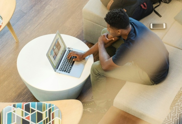 Top level view of person working on their laptop on a couch