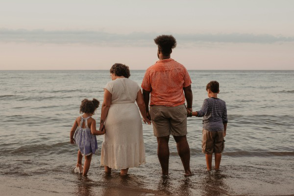 family holding hands standing in water at the beach