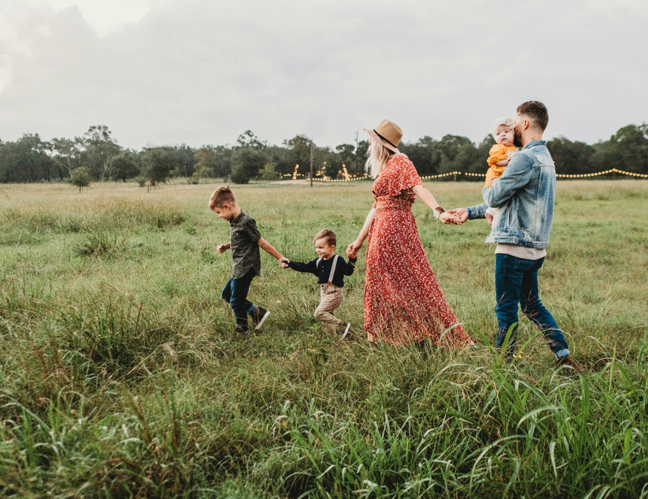 family holding hand and walking in fields for photoshoot