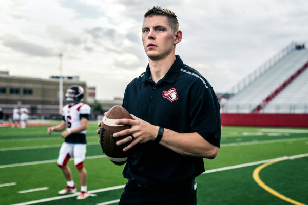 coach holding football watching players