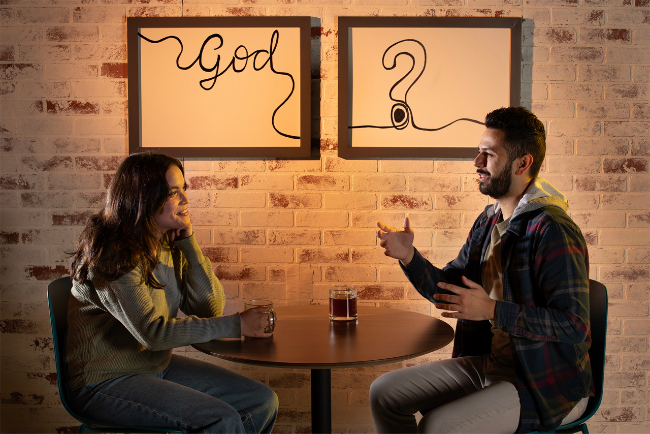 People sitting at coffee shop with signs representing God questions in the background.