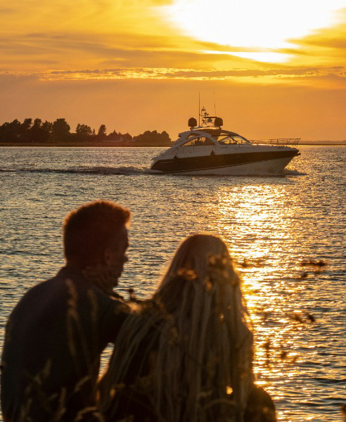 Silhouette of couple watching the sunset and a boat in the distance