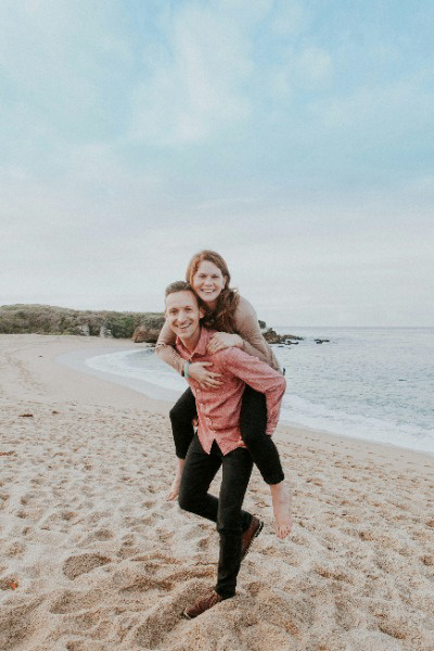 Husband holding wife on back smiling for beach photoshoot