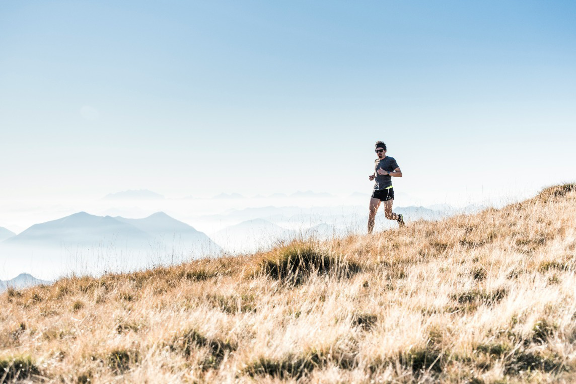 person running through fields in the mountains