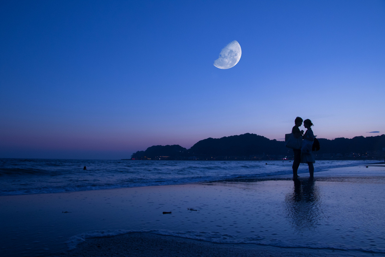 Silhouette of couple standing on a beach with the moon and blue hour