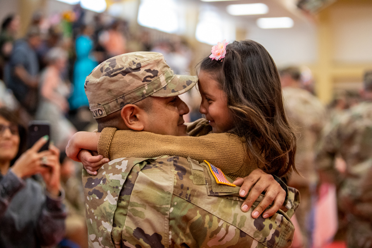 soldier holding daughter and smiling at her