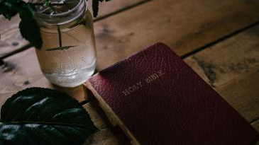 Bible on a table with a cup of water.
