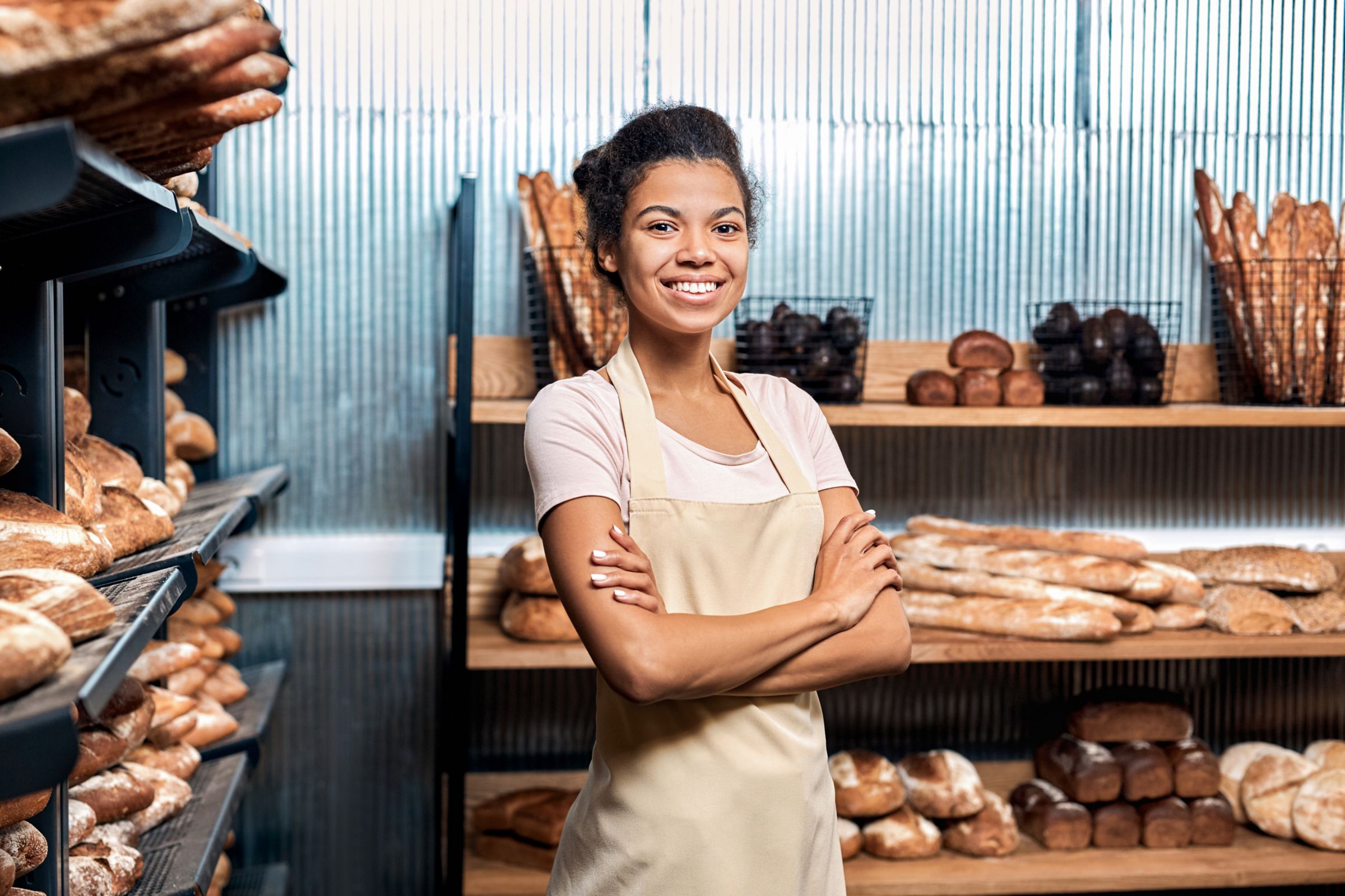a woman in an apron standing in front of a shelf of bread