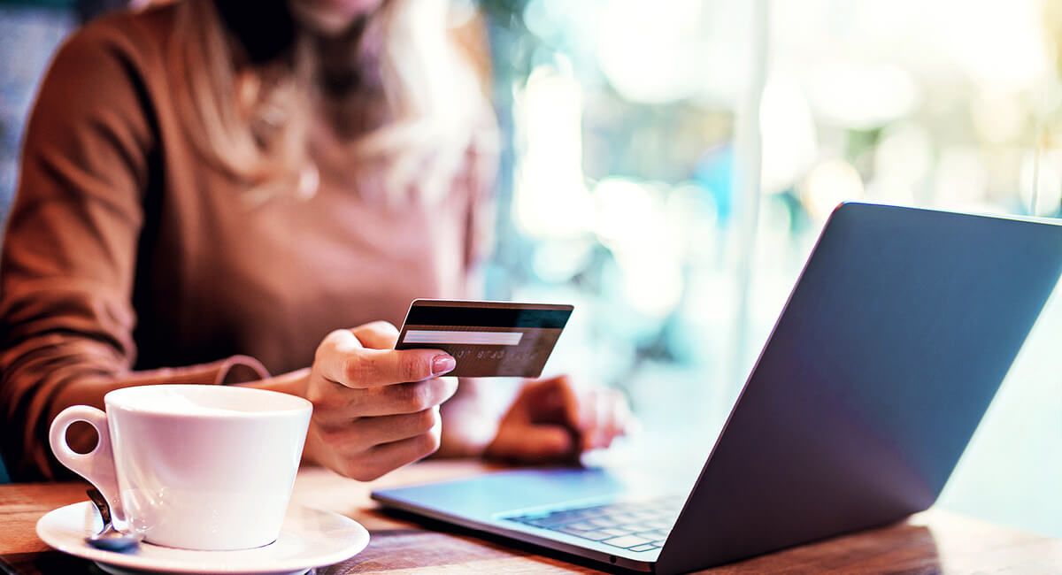 a person holding a credit card and using a laptop