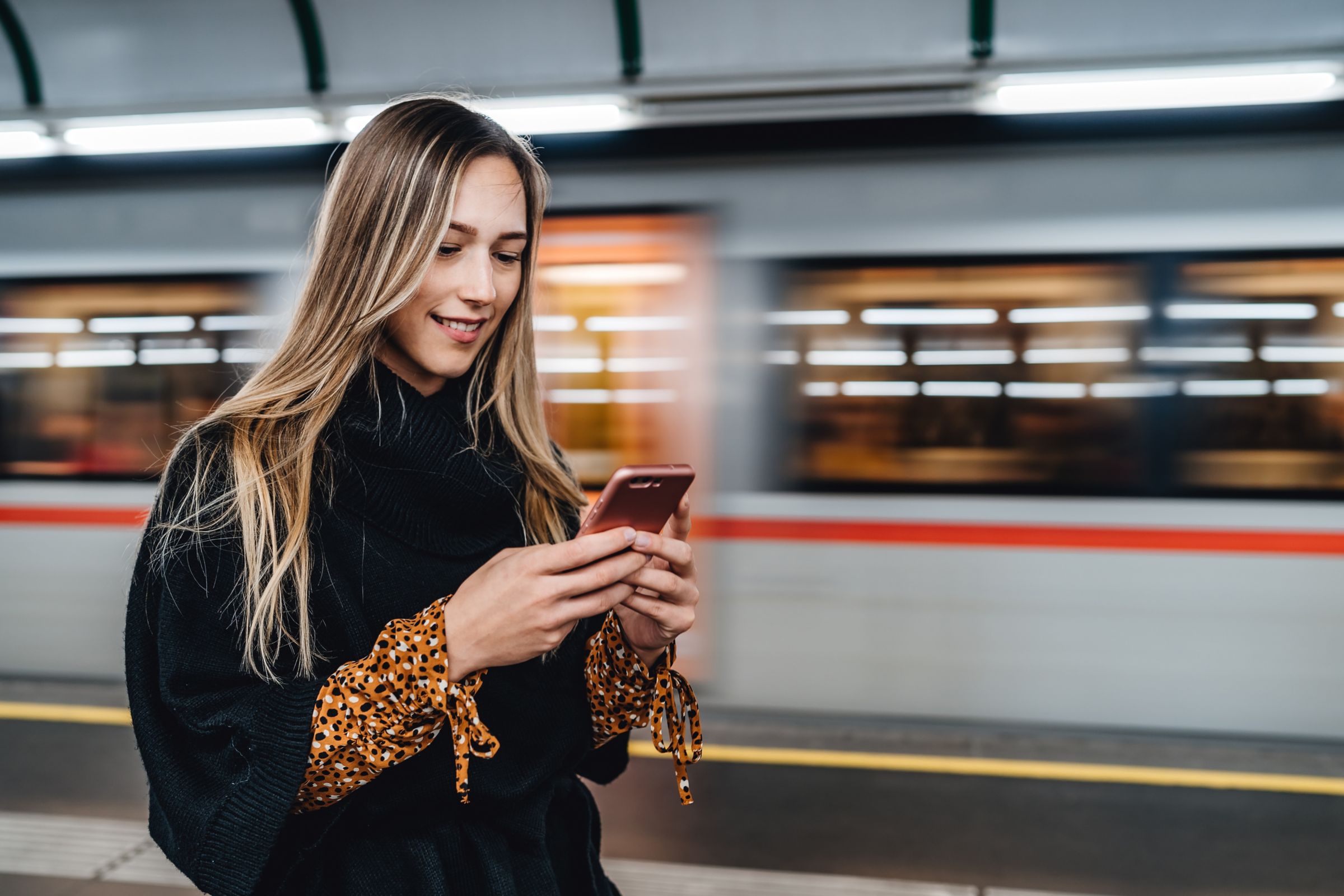 woman checking ride schedule for subway train on smartphone