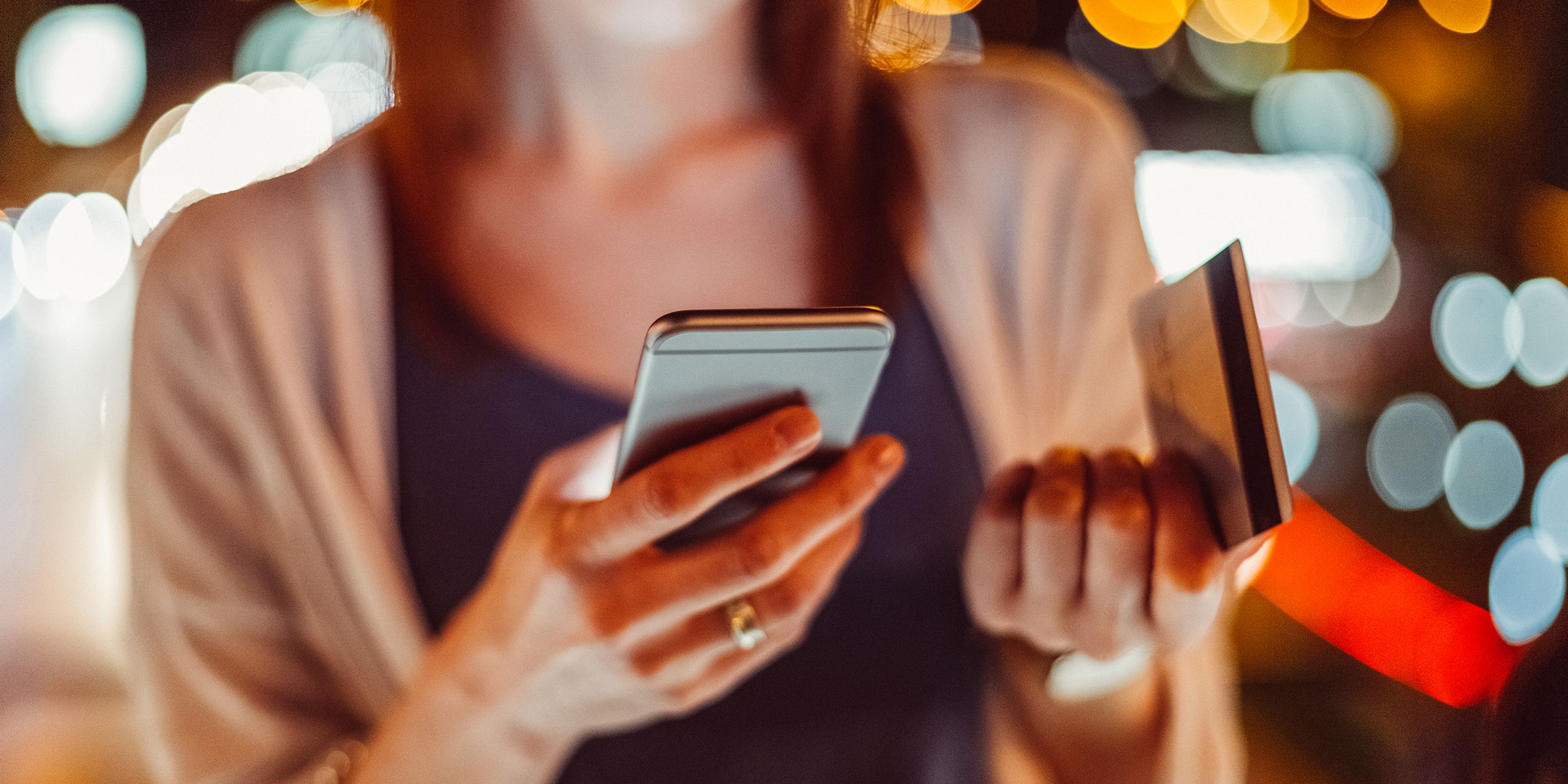 una mujer con un teléfono y una tarjeta electrónica en la mano