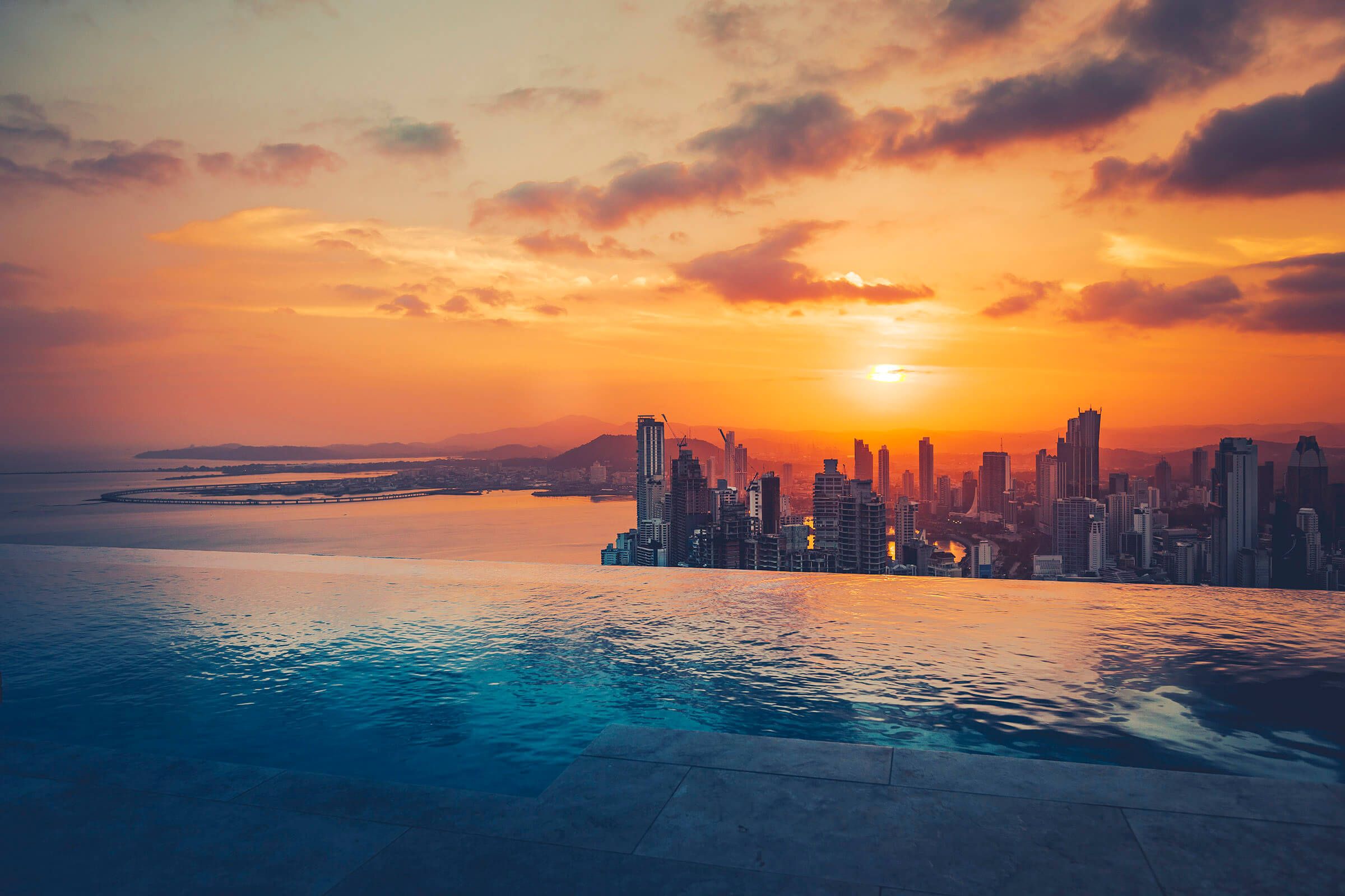 a water pool with a city skyline and a sunset
