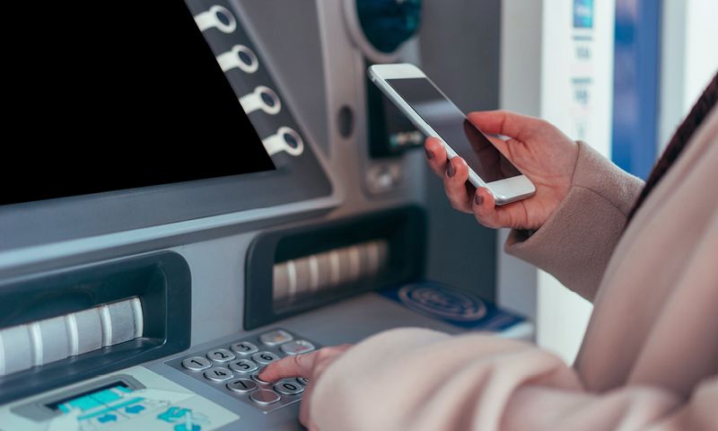 Woman using phone at ATM