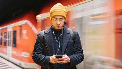 Person on a subway platform looking at their phone.