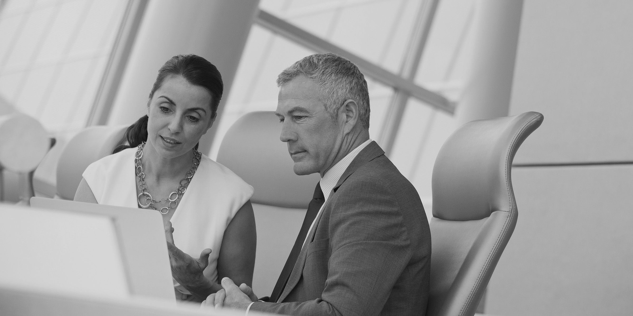 Business people in a discussion; a female-presenting person on the left is leading the male-presenting person on the right in discussion