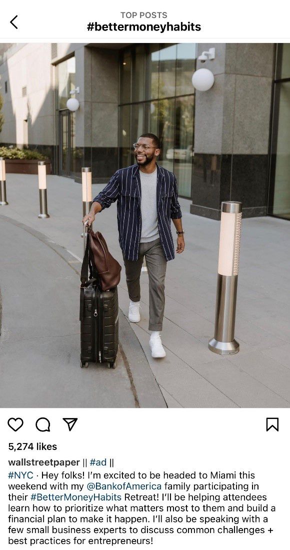 A screenshot of an Instagram post featuring a male-presenting person in casual attire walking along a city street with a suitcase while smiling away from the camera. The caption of the post describes how they are going to Bank of America's Better Money Habits Retreat.