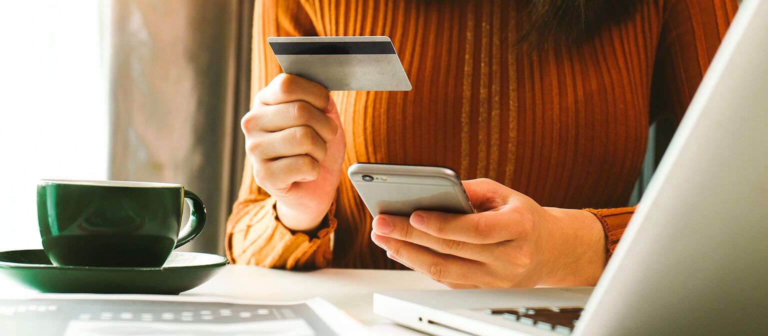 Woman on computer holding credit card