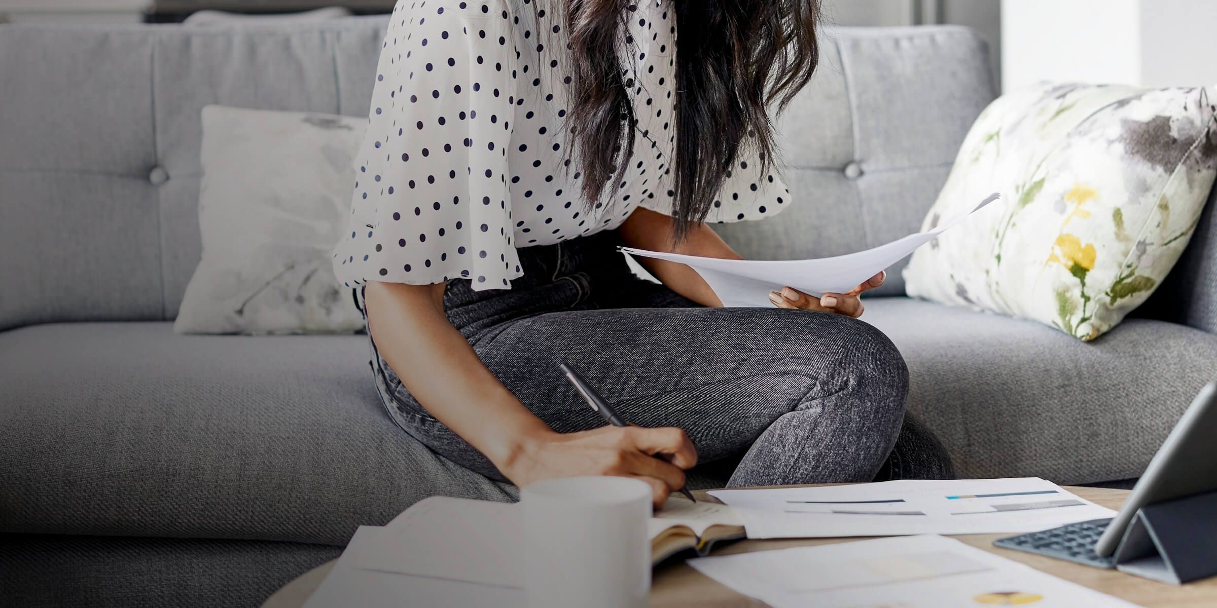 a woman sitting on a couch writing on paper