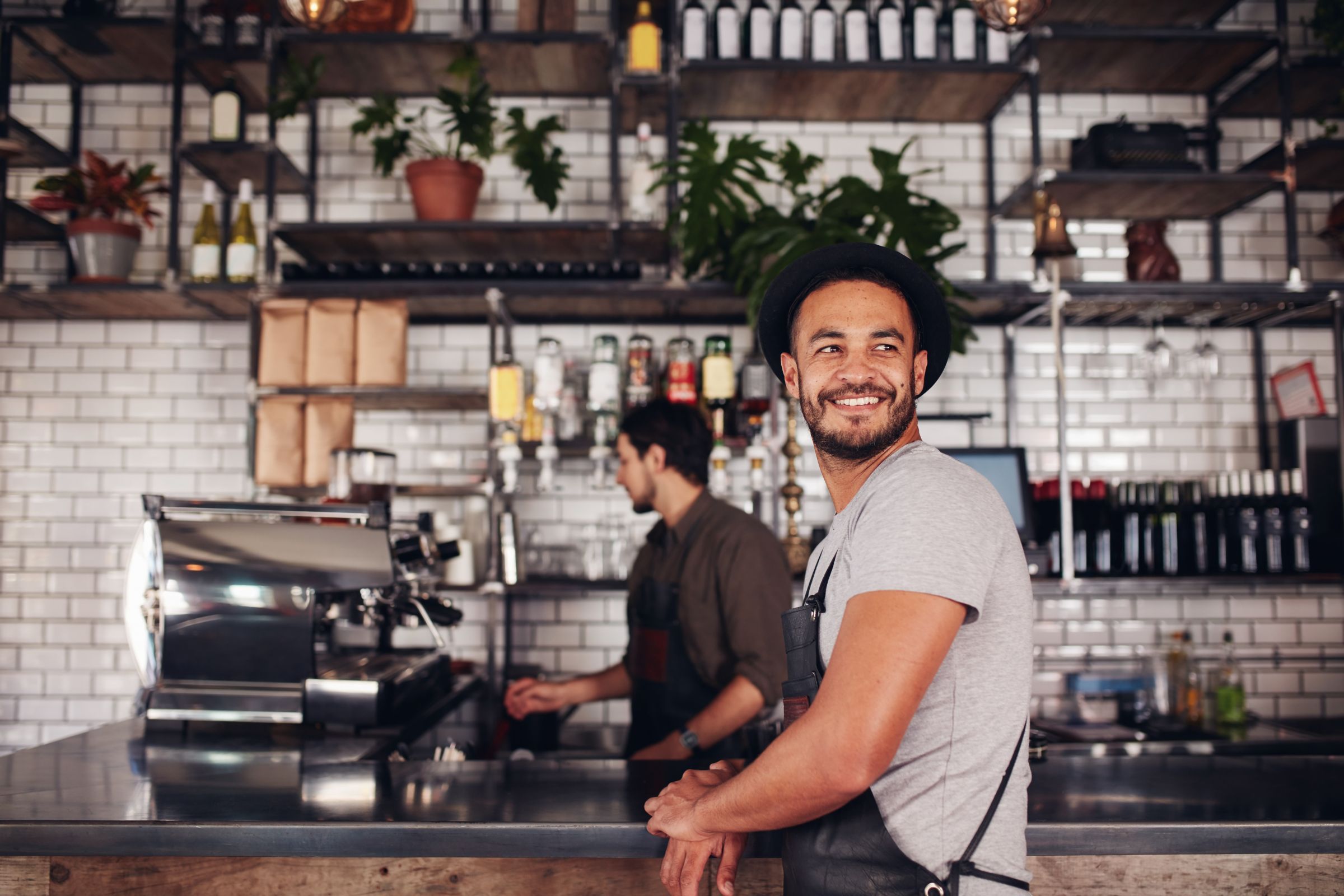 Coffee shop owner standing with barista working behind the counter making drinks.