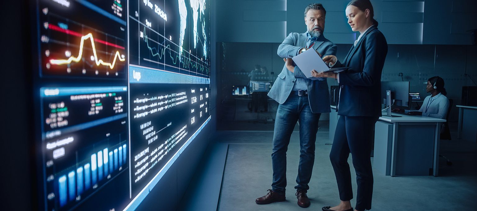 Two men standing in server room looking at laptop