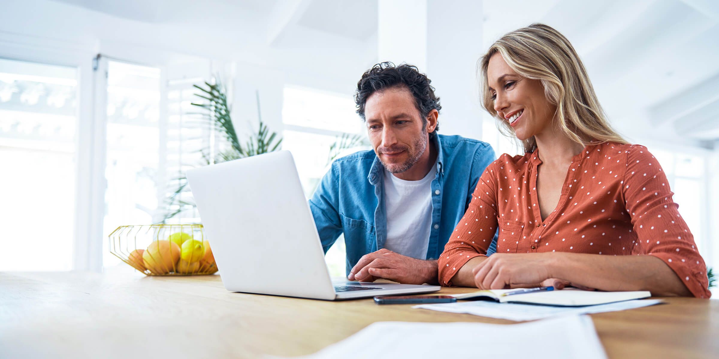 Two people sitting at a table using a laptop computer.