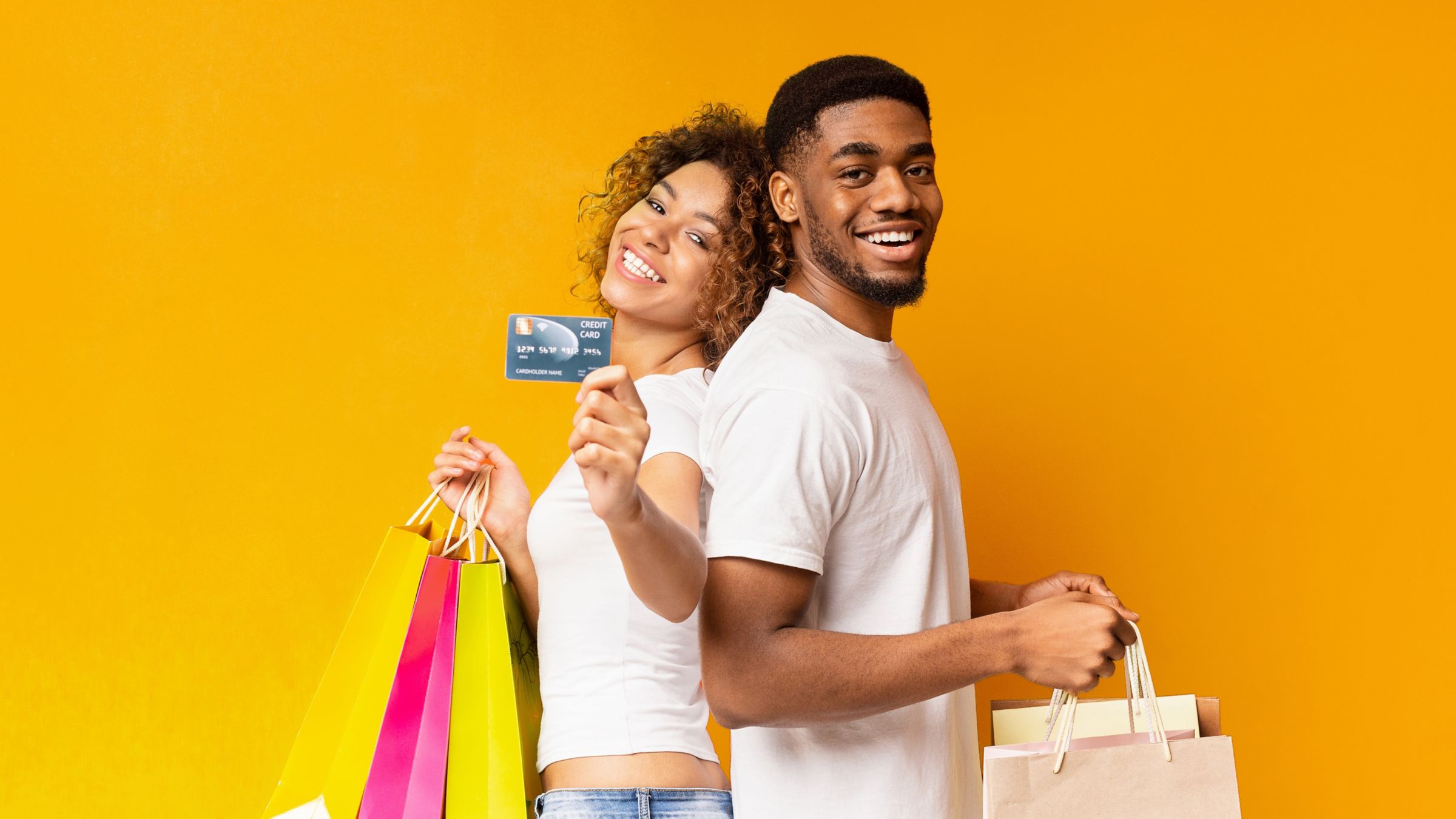 Couple smiling holding credit card and shopping bags