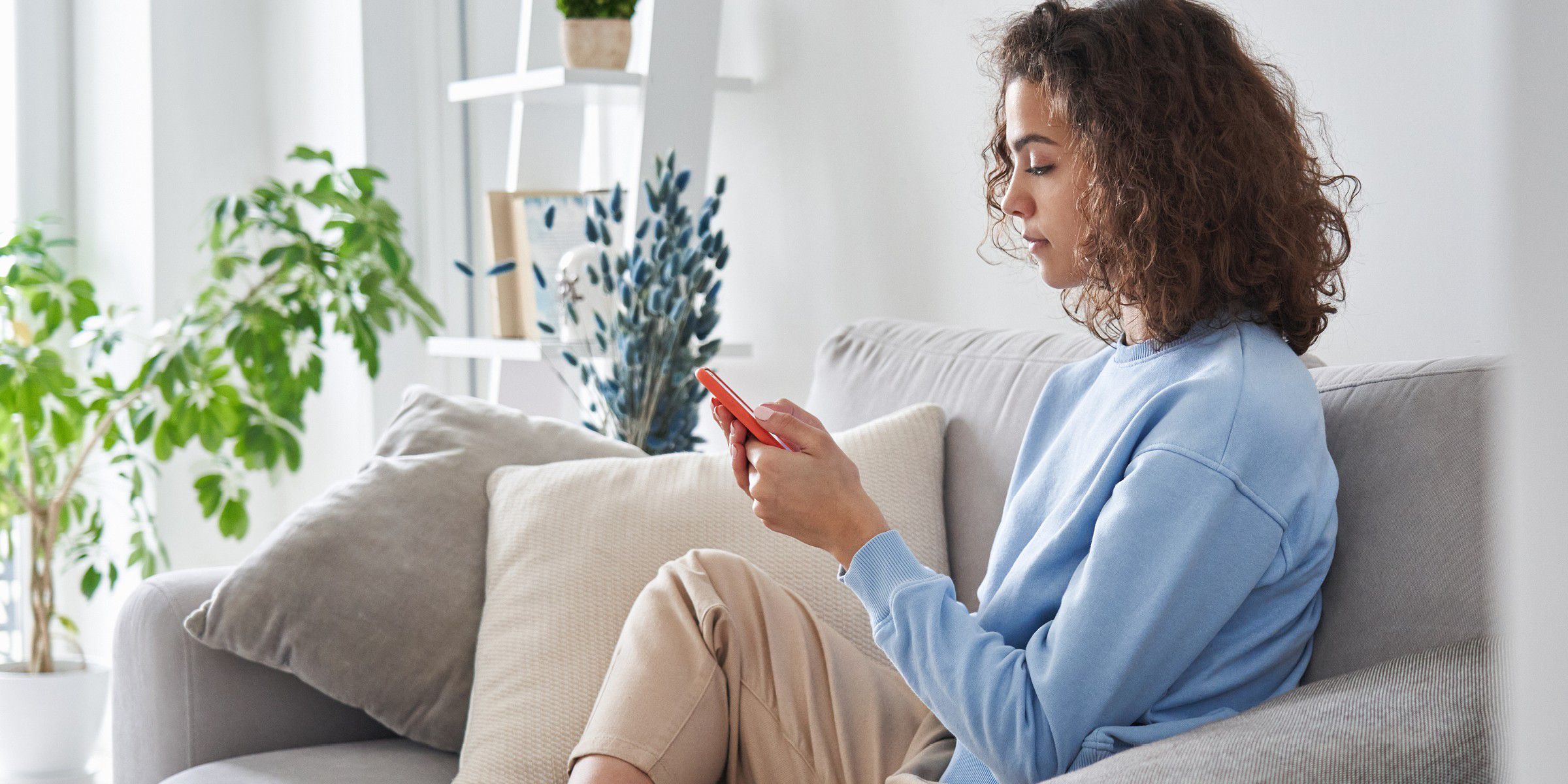 Woman sitting on sofa looking at phone