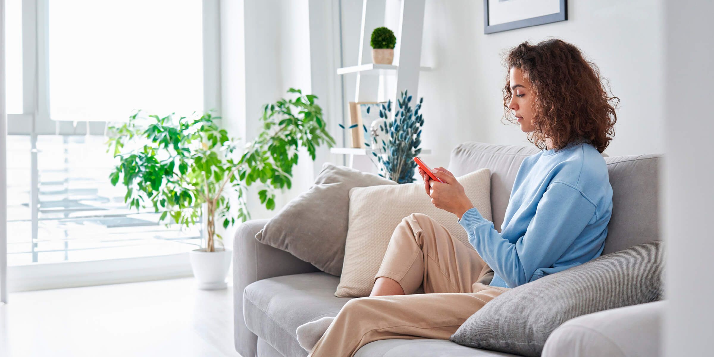 Person using their smartphone while sitting on a couch.