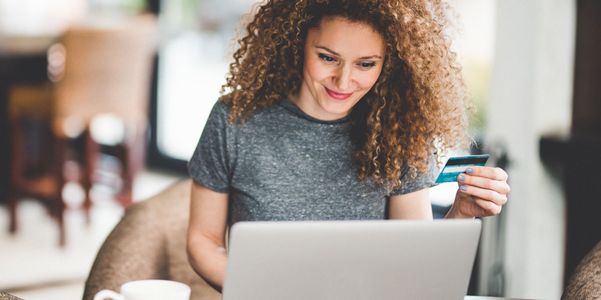 A person looking at the laptop and holding a electronic card