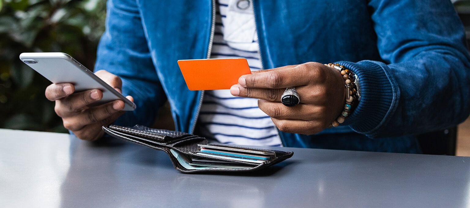 Young man holding phone and credit card smiling