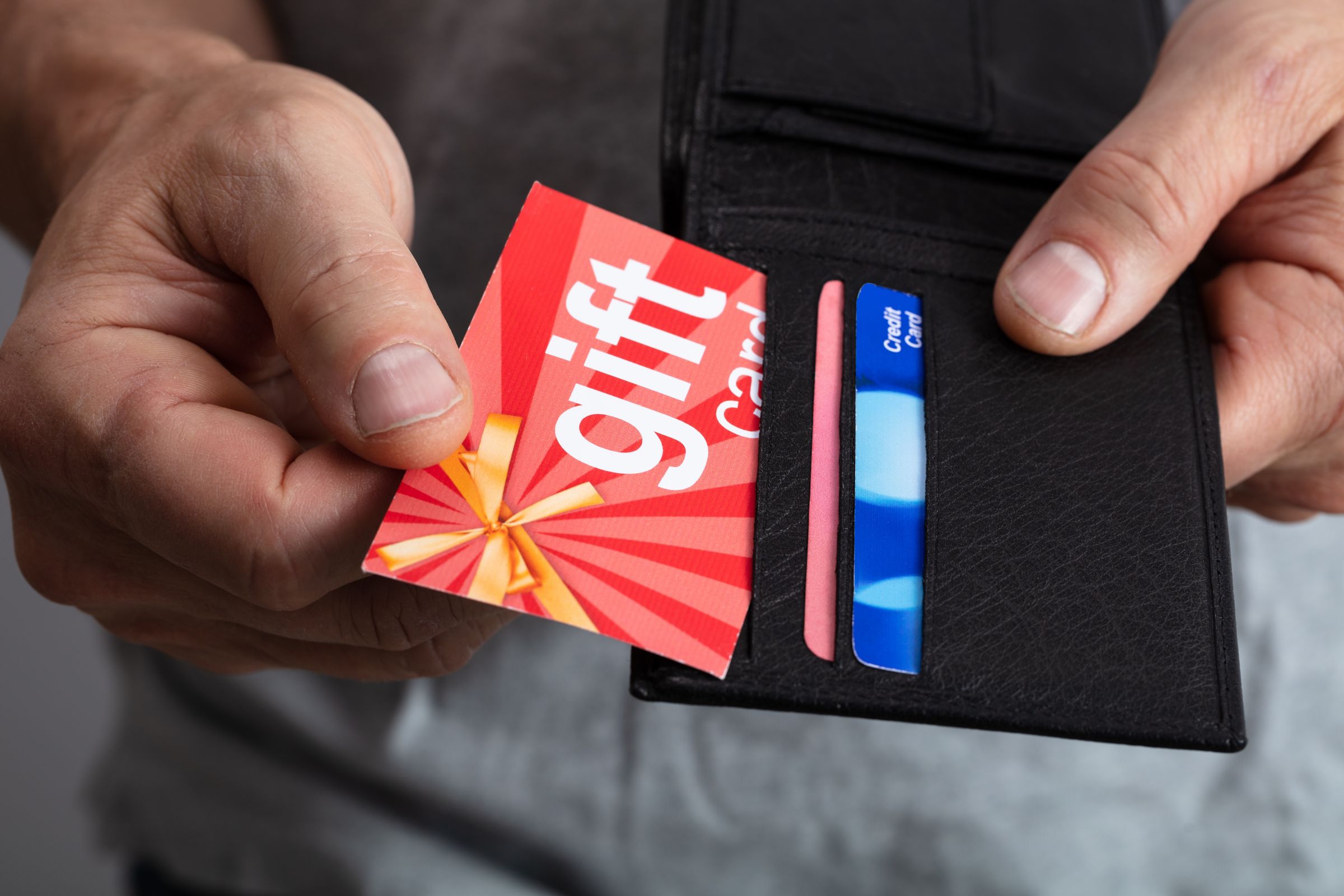 Close up of person taking red gift card from wallet.