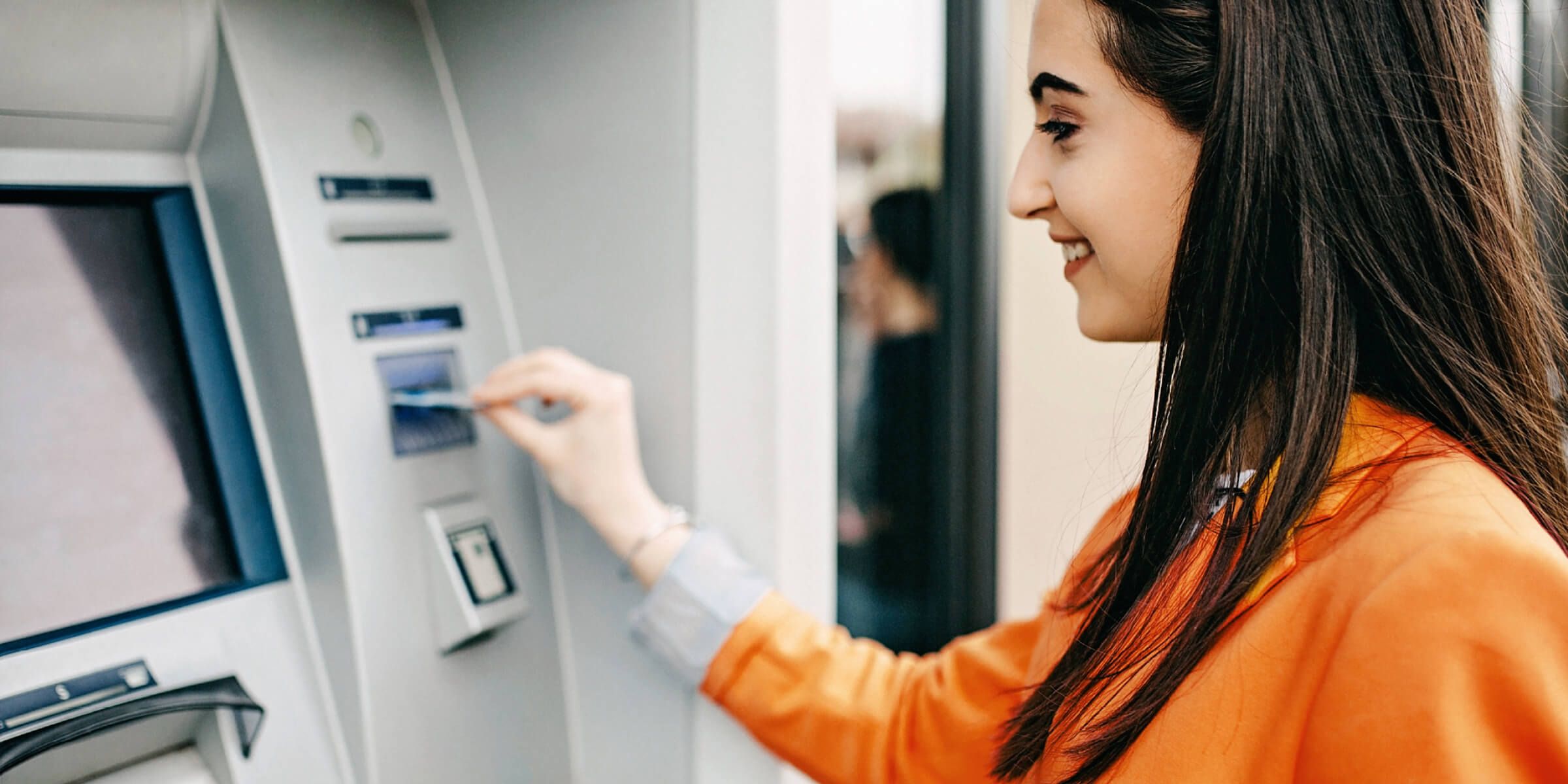 a woman is using an electronic card at the ATM