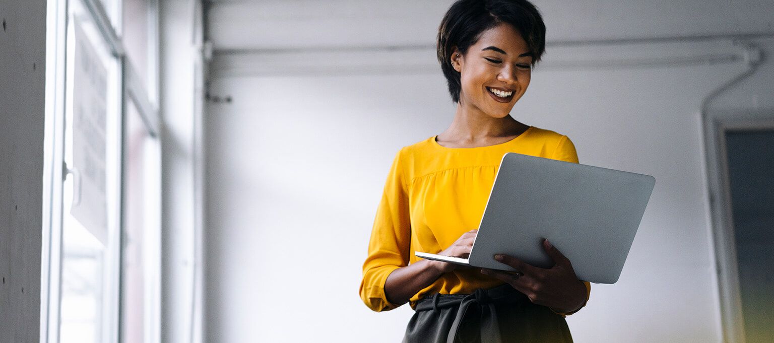 a woman in a yellow shirt holding a laptop