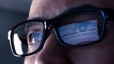 Man wearing glasses with computer reflected in lenses