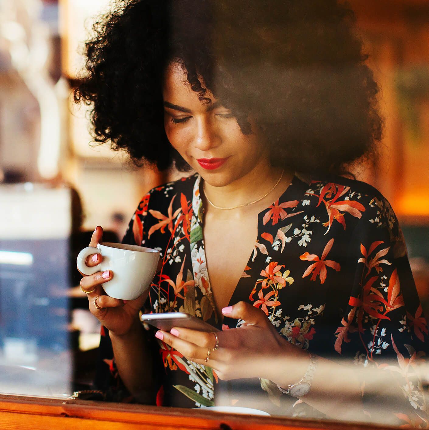 woman looking at her phone holding coffee