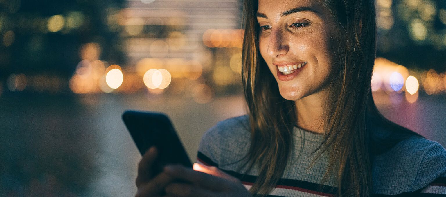 A smiling woman checks her mobile phone