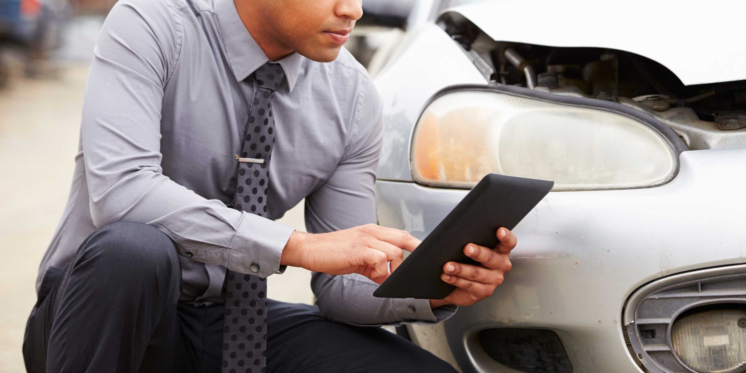 a man is sitting in the front of a car, looking at a tablet