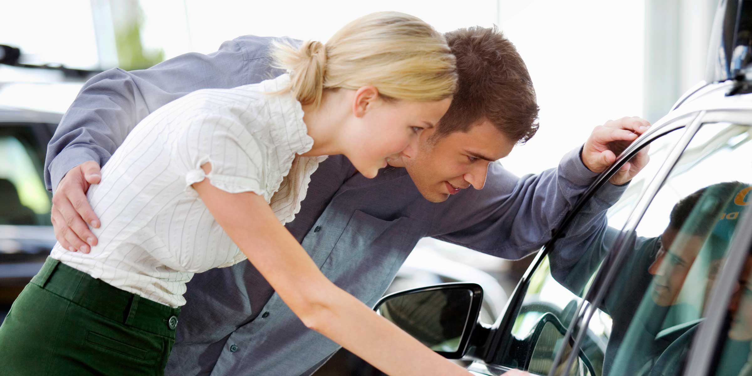 a man and woman looking at a car