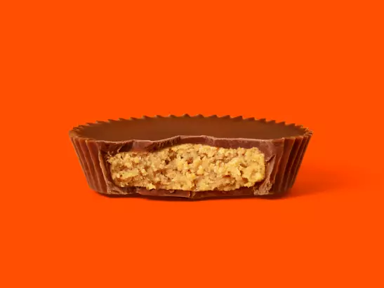 https://s7d2.scene7.com/is/image/hersheysassets/181112_REESES_STDCUP_SINGLE_BITE_280_LAYERED_FINAL?fmt=webp-alpha&hei=411&qlt=75