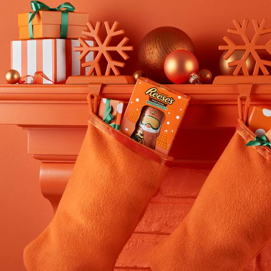 REESE'S Peanut Butter Snowman packages inside holiday stockings hanging from mantle