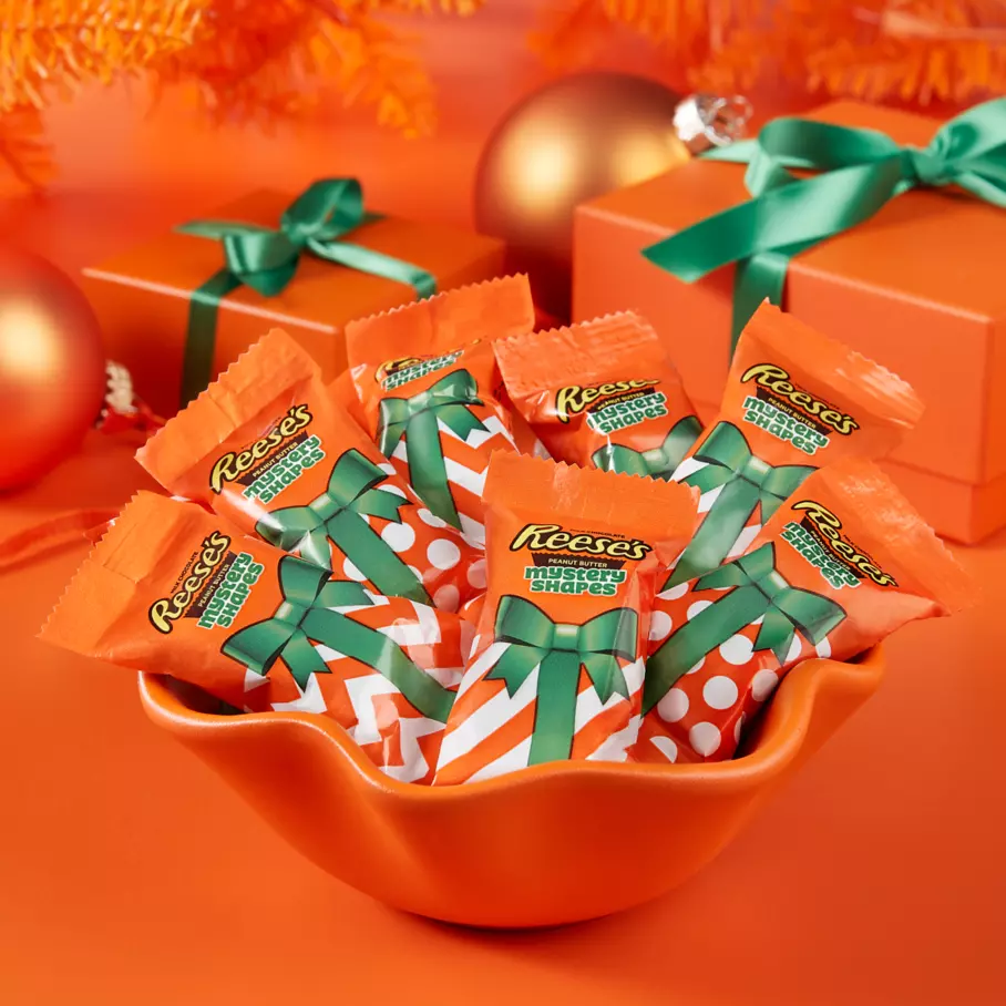 REESE'S Mystery Shapes inside decorative bowl surrounded by gifts and ornaments