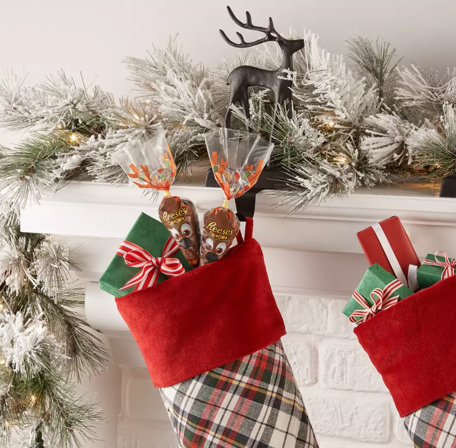 REESE'S PIECES Reindeer Candy Carrots hanging inside stockings along mantle