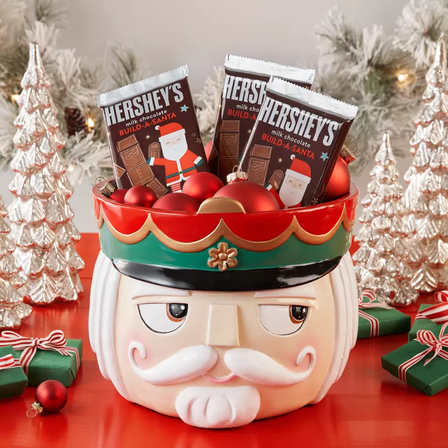 HERSHEY'S Build-A-Santa Candy Bars inside nutcracker bowl surrounded by ornaments