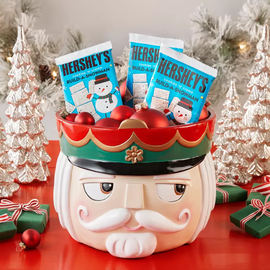 HERSHEY'S Build-A-Snowman Candy Bars inside nutcracker bowl surrounded by ornaments