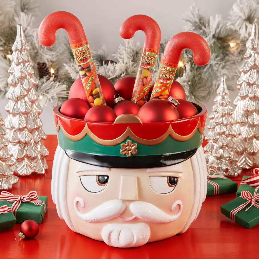 REESE'S PIECES Holiday Candy inside nutcracker bowl surrounded by ornaments