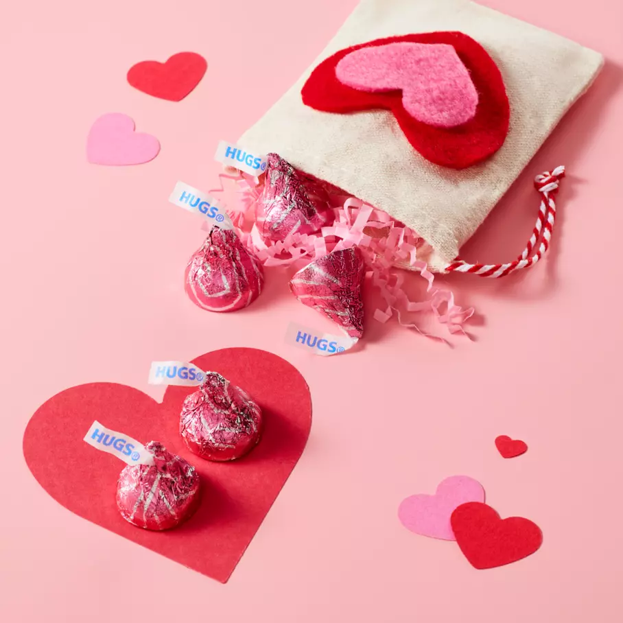 HERSHEY'S HUGS spread out on pink heart background