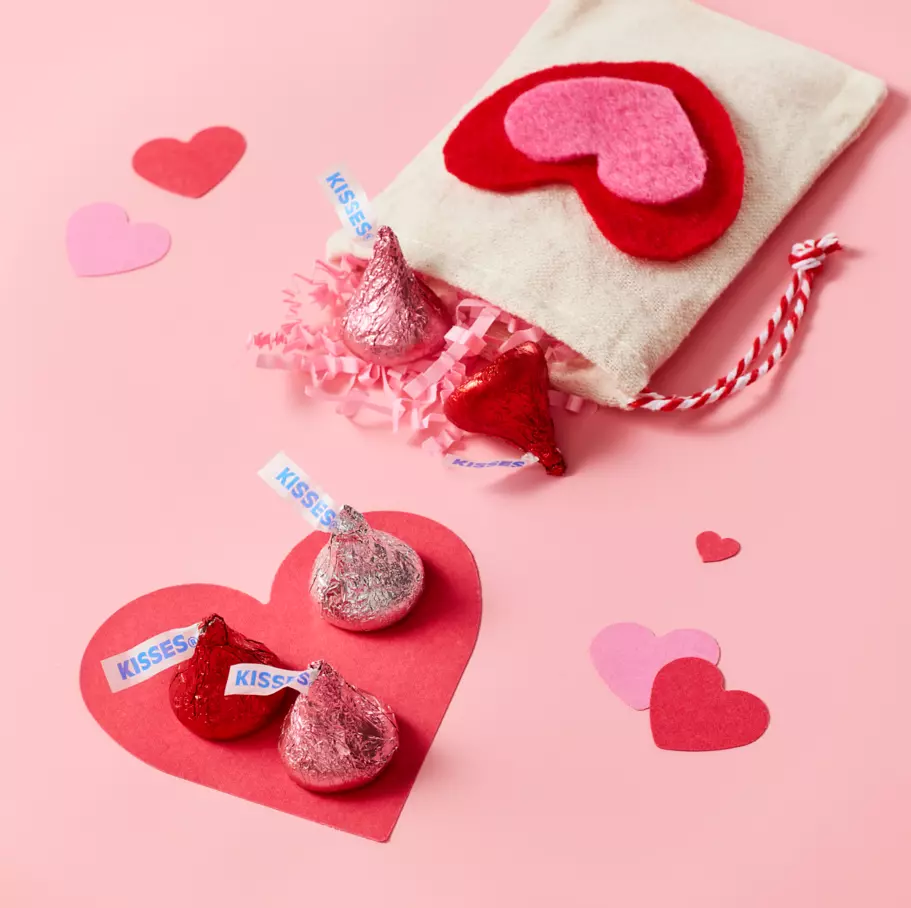 HERSHEY'S KISSES candy spread out on pink heart background