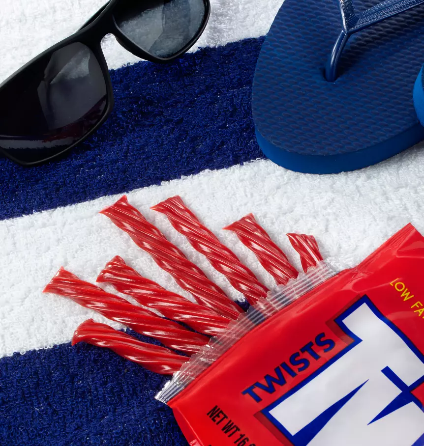 twizzlers on beach towel next to sunglasses and flipflops
