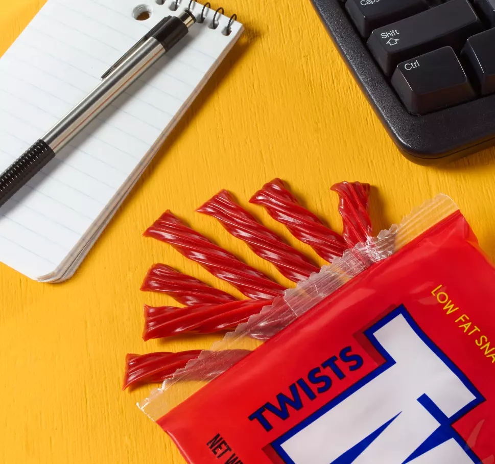 twizzlers next to keyboard and pad of paper with pen