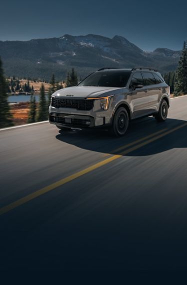 2026 Kia Sorento, three-quarter driver's-side view, driving on a road in the mountains.